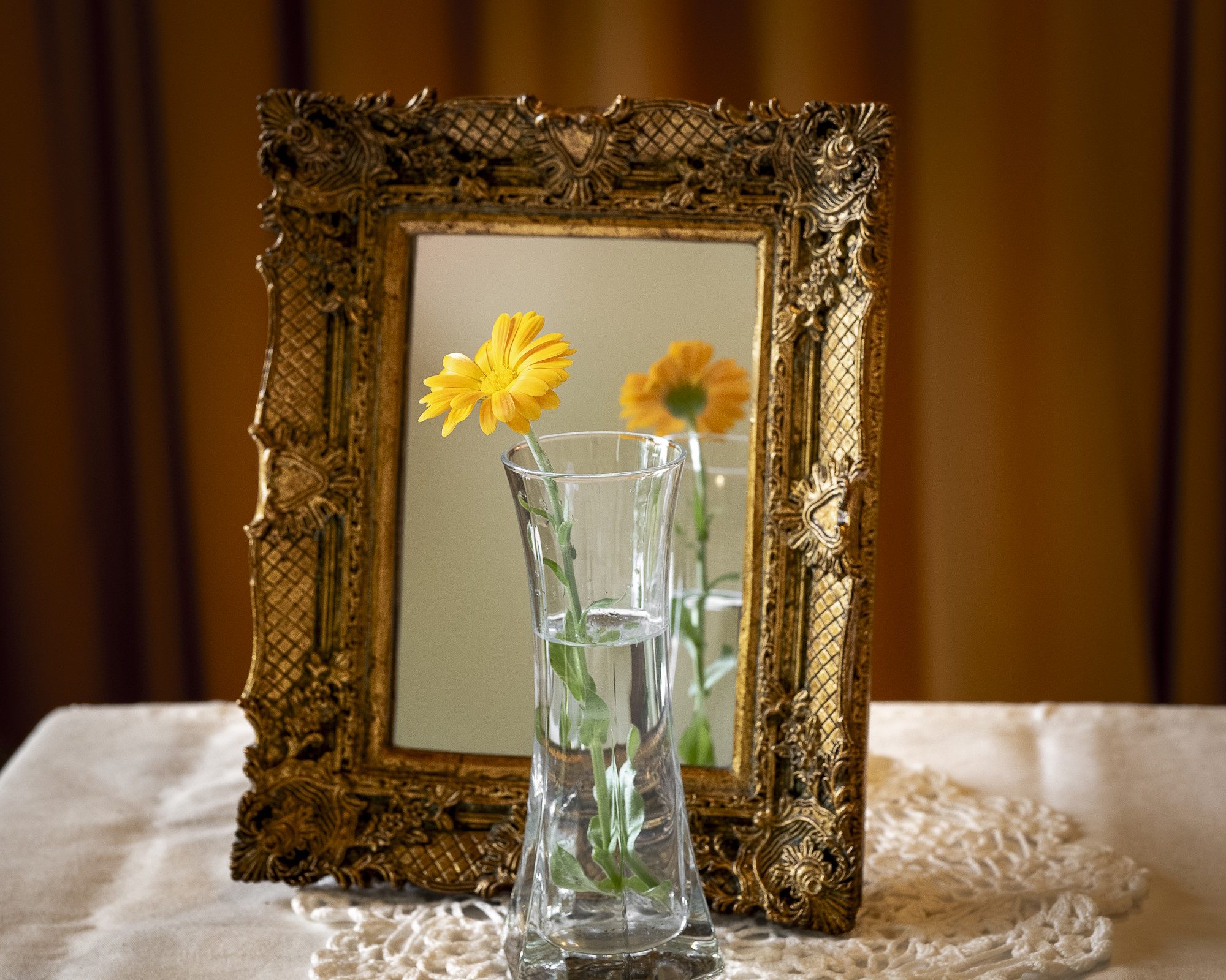 Vaso con fiore giallo e specchio da tavolo